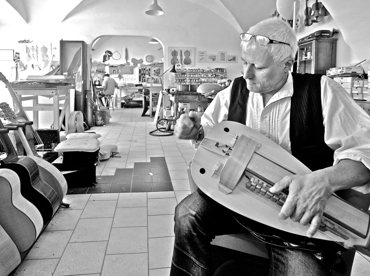 Instrumentenbauer spielt ein Instrument in seiner Werkstatt