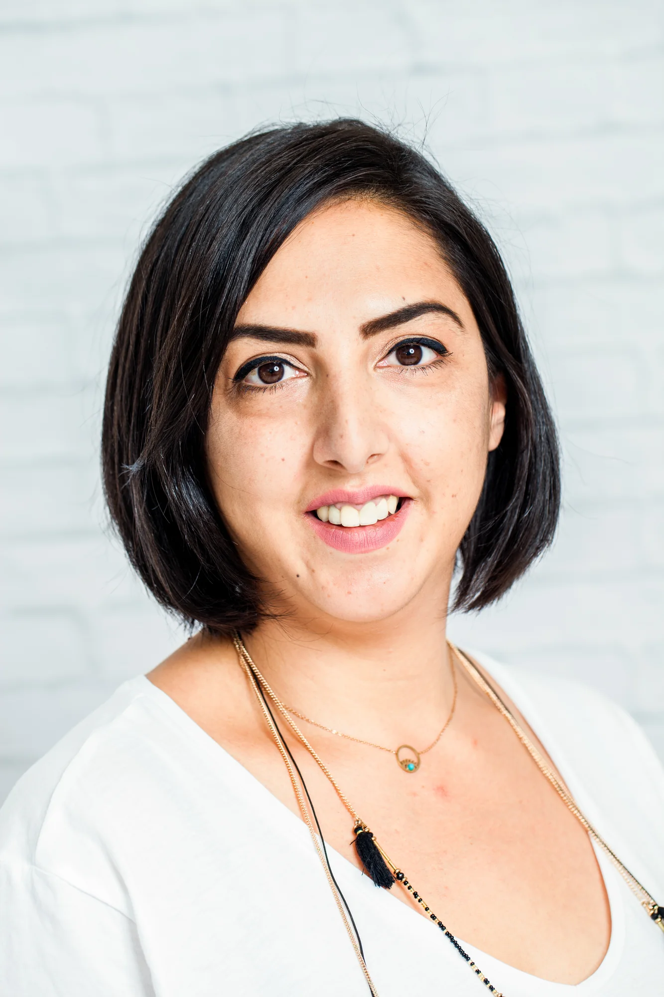 Freundlicher Business-Headshot einer Frau vor heller Wand